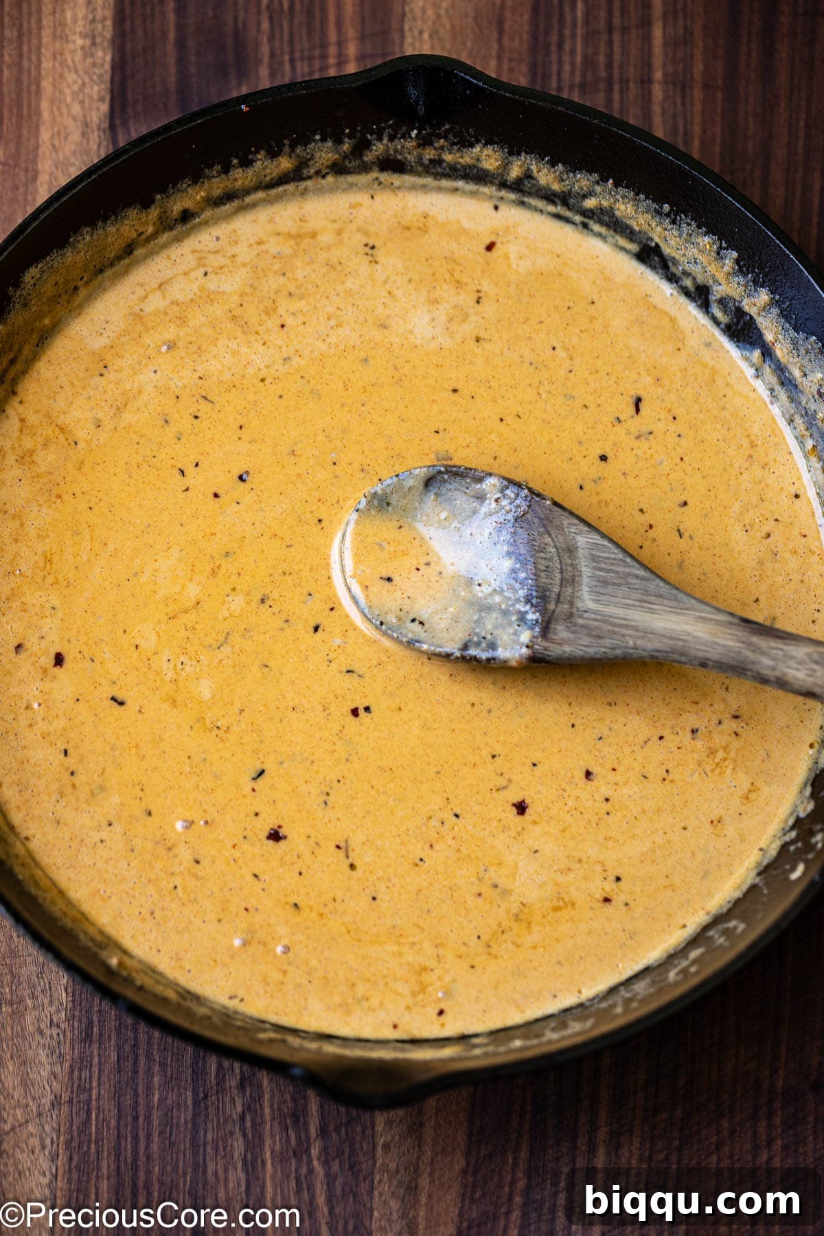 Stirring a creamy Cajun pasta sauce in a skillet.