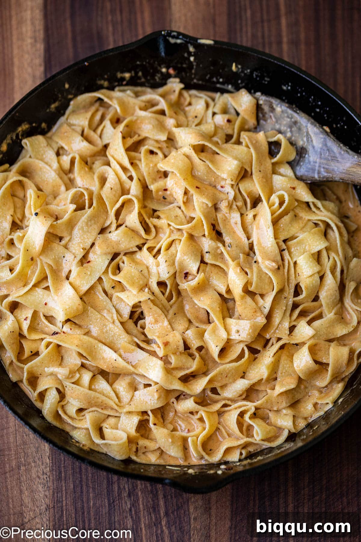Mixing cooked pappardelle pasta with the creamy Cajun sauce.