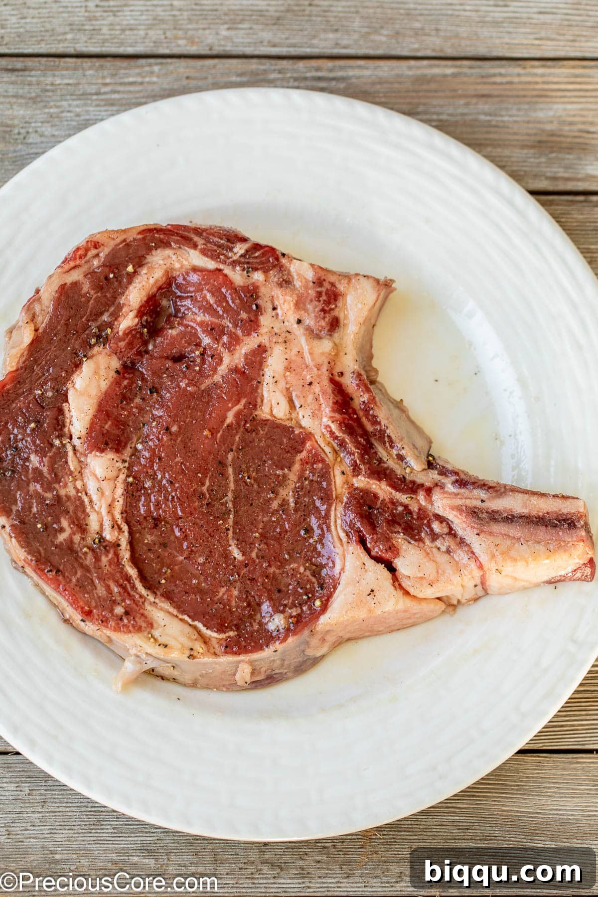 Bone-in steak seasoned with salt and pepper.