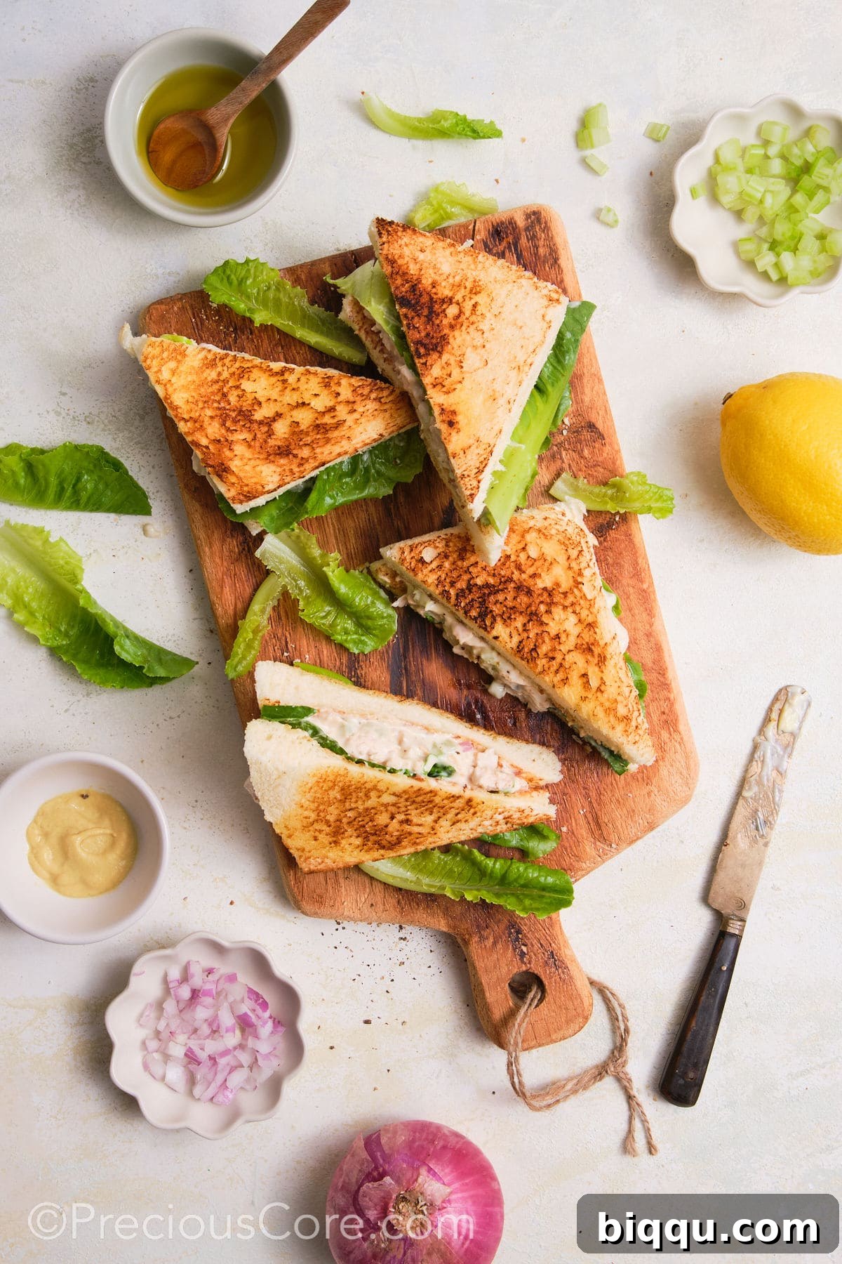 Cut chicken mayonnaise sandwiches on a cutting board.