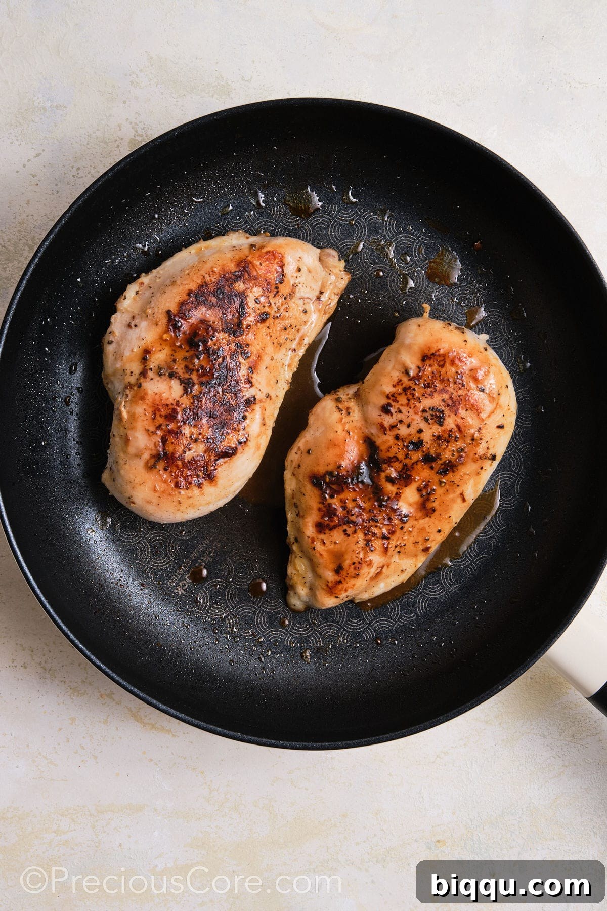 Searing chicken breasts in a skillet.