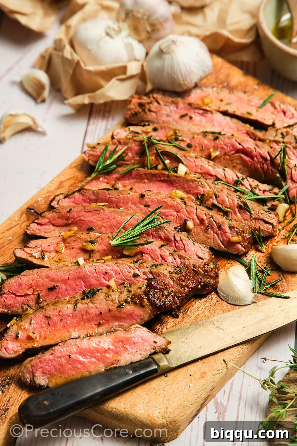 Sliced pan seared flank steak on a cutting board, ready to serve.
