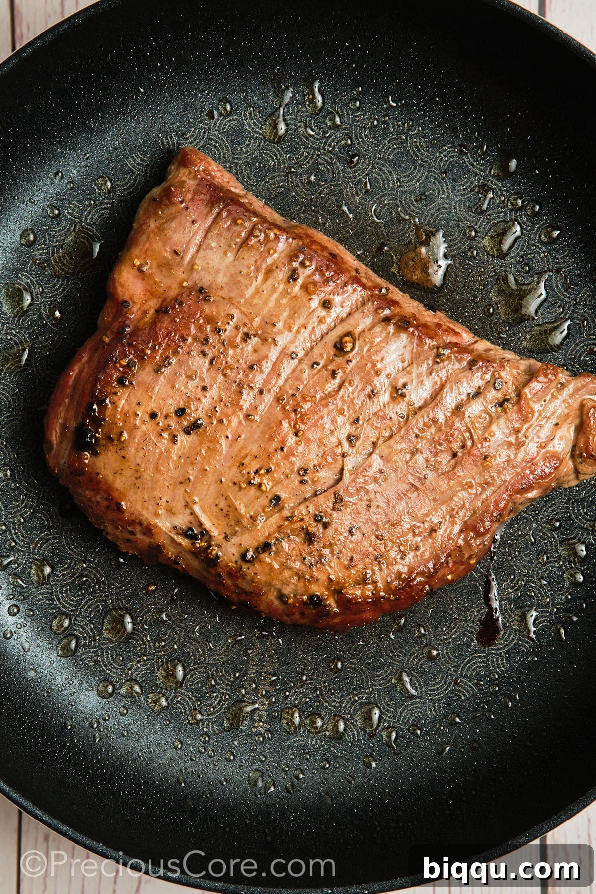 Searing a piece of flank steak in a hot skillet for a perfect crust.