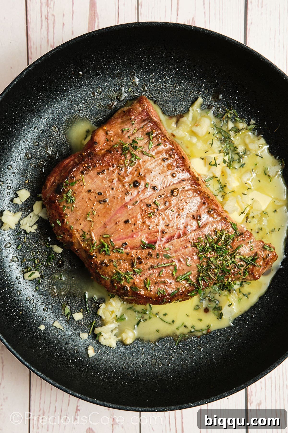 Butter added to pan with steak, ready for garlic and herbs.