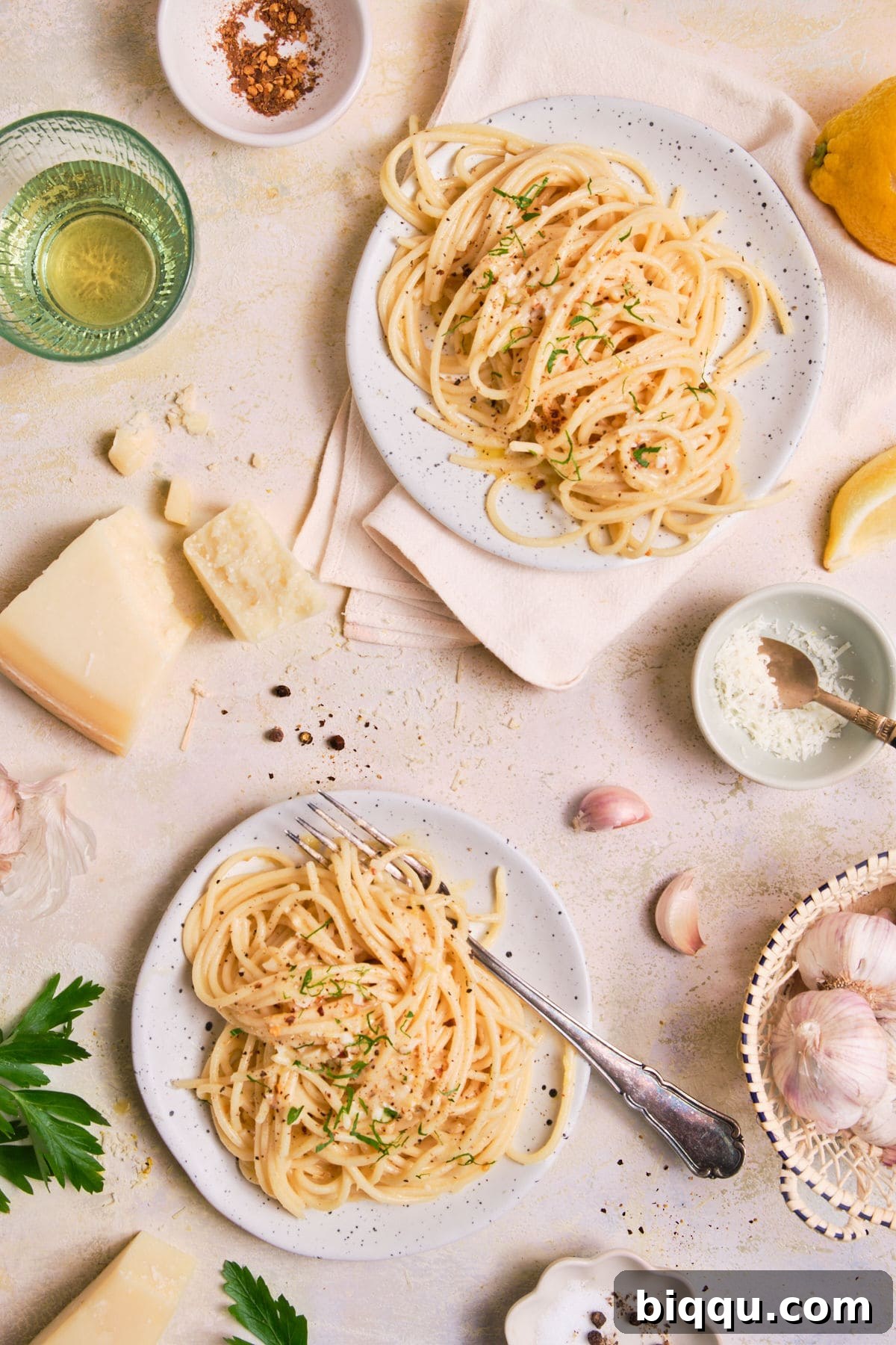 Zesty Lemon Garlic Butter Pasta 3 Two plates of Lemon Garlic Butter Pasta topped with grated parmesan and fresh herbs.
