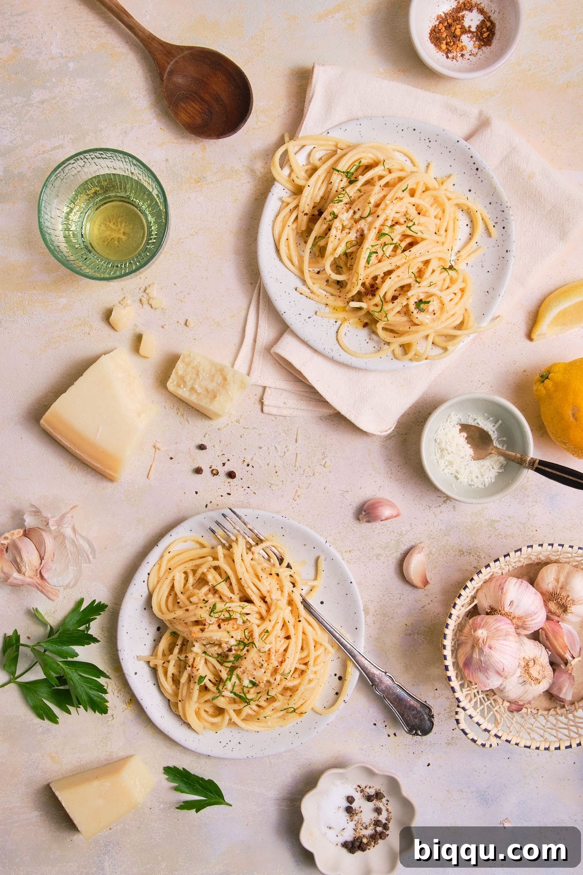 Zesty Lemon Garlic Butter Pasta 8 Two plates of swirled spaghetti garnished with fresh parsley and black pepper.
