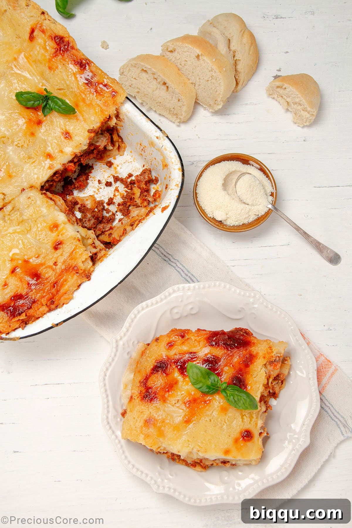 A perfectly portioned slice of golden-baked lasagna on a plate, with a large, bubbling baking dish of fresh lasagna in the background, ready to be served.