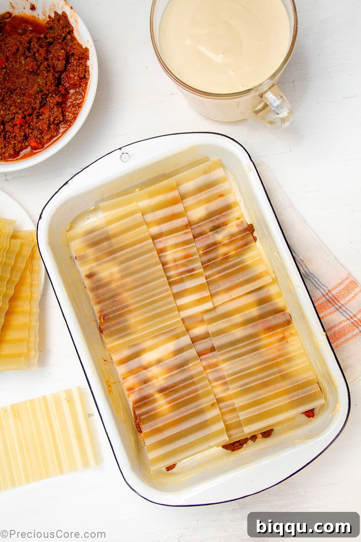 Layers of no-boil lasagna noodles carefully placed over a base of meat sauce in a baking dish.