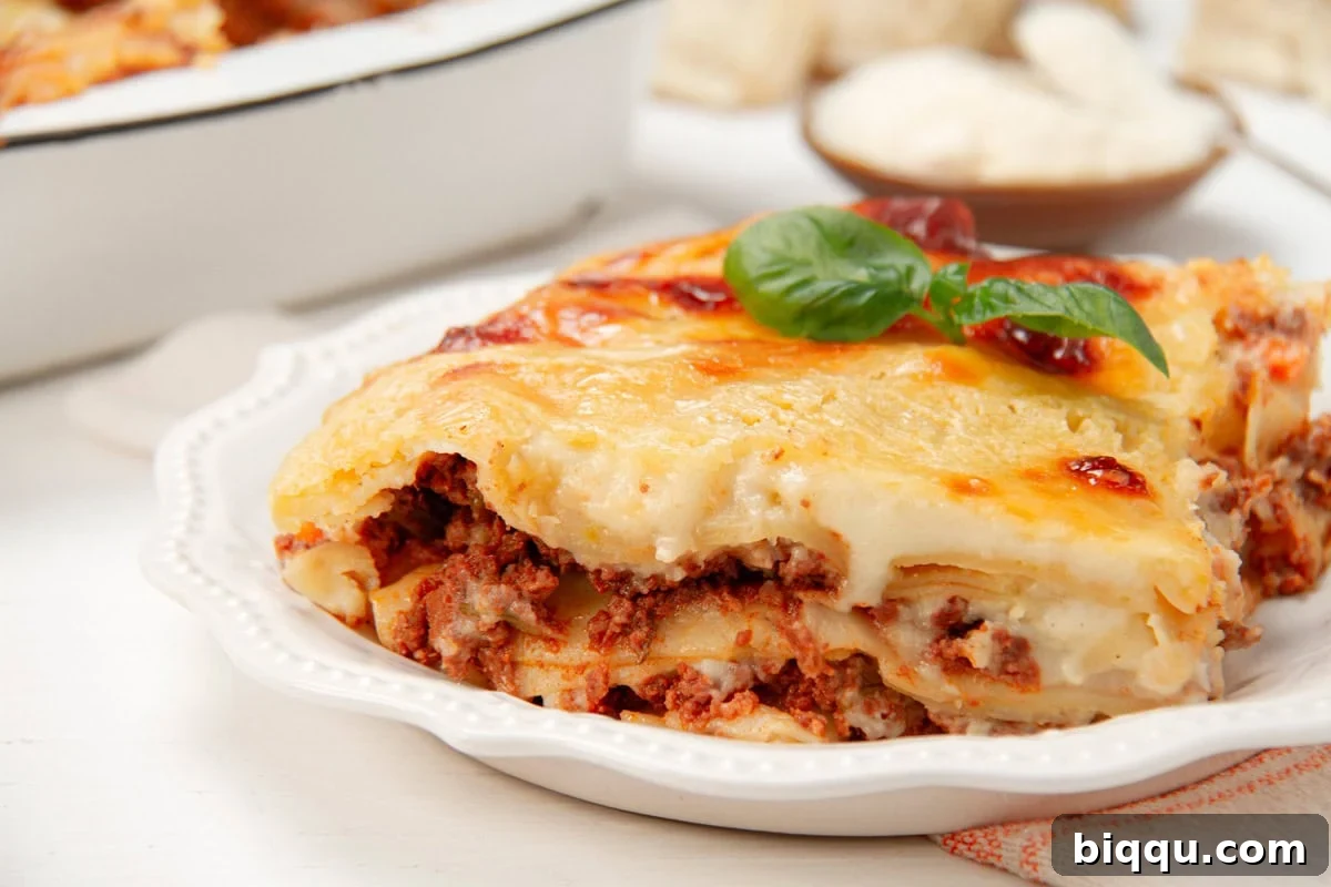An inviting close-up of a perfectly baked slice of lasagna, revealing the distinct layers of pasta, rich meat sauce, and creamy béchamel, topped with melted cheese.