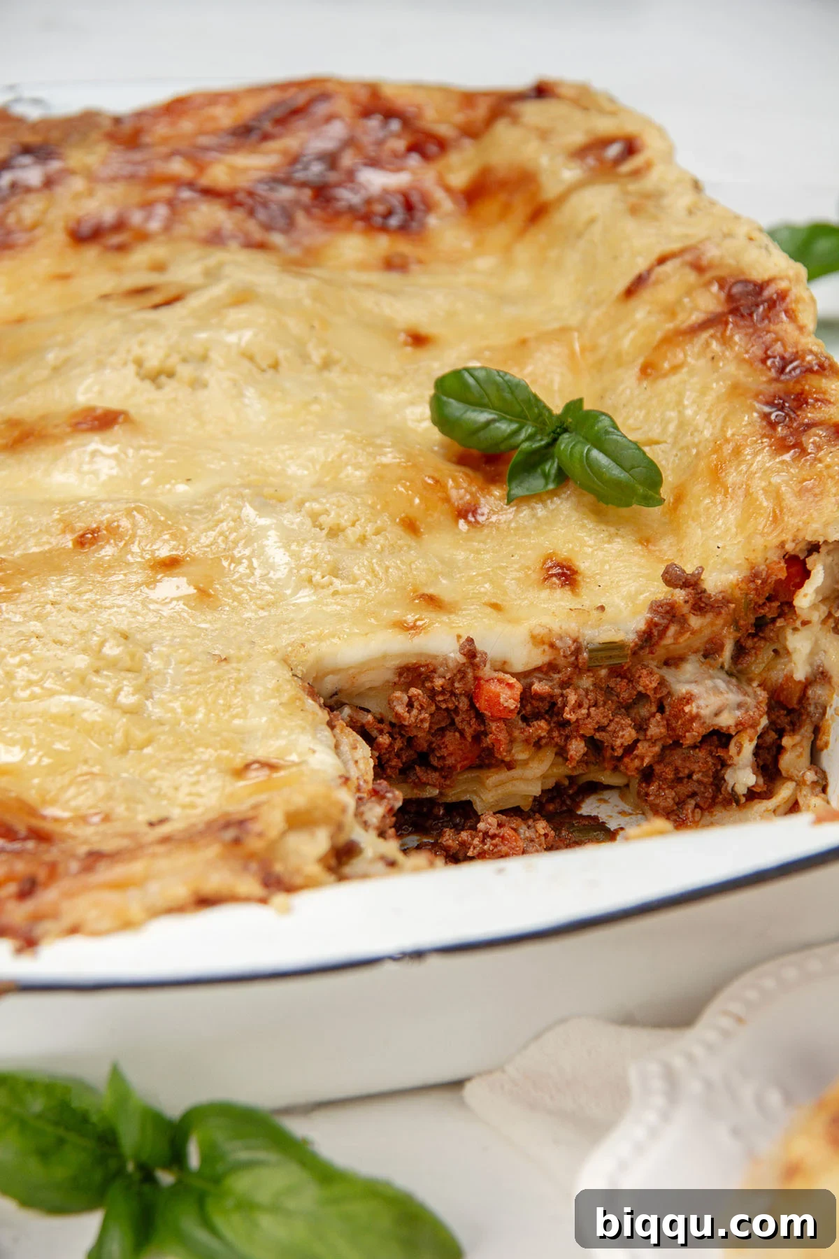 A generous portion of freshly baked lasagna with a golden-brown béchamel topping, served directly from the dish.