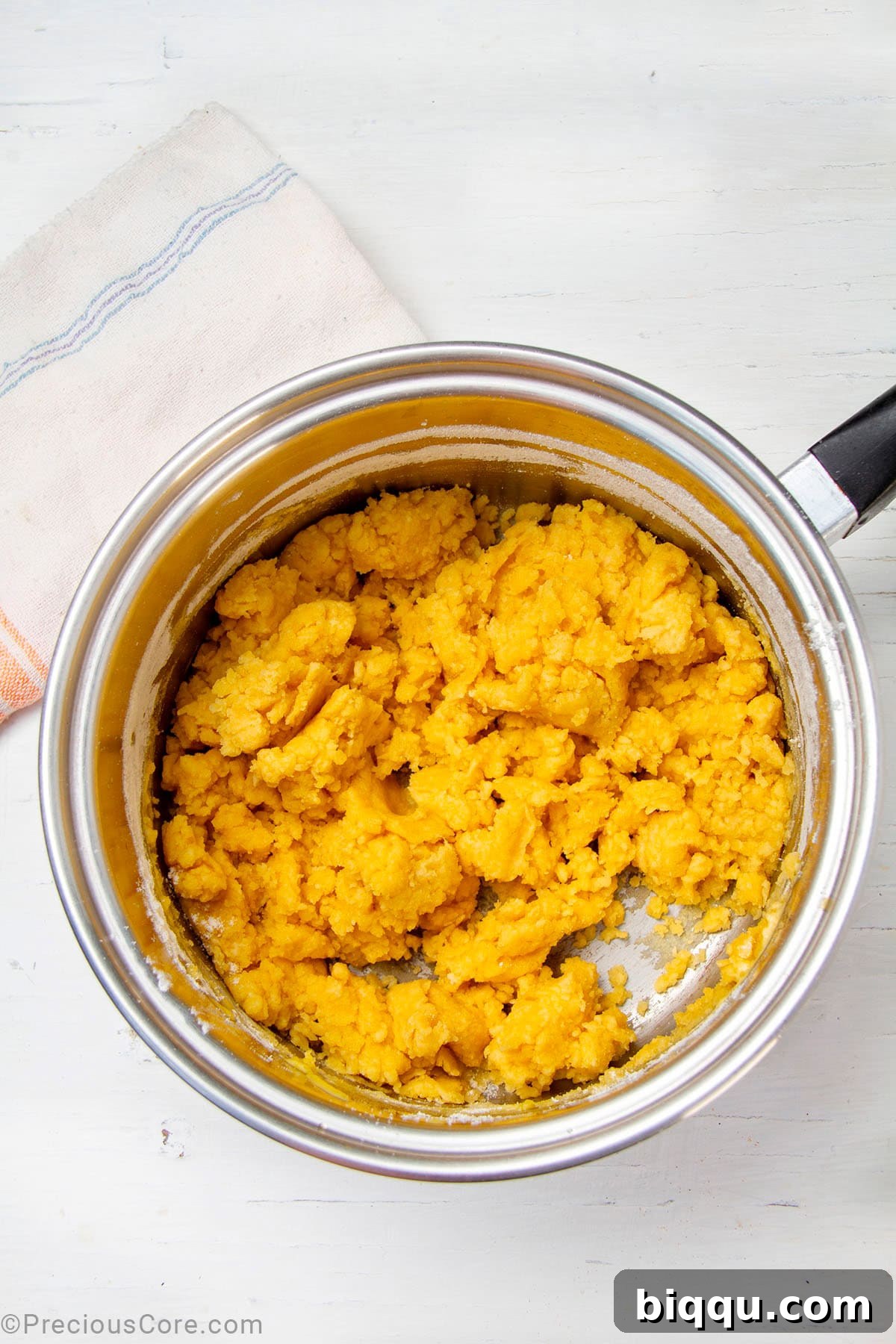 A golden-brown roux, a smooth mixture of flour and butter, cooking in a saucepan.
