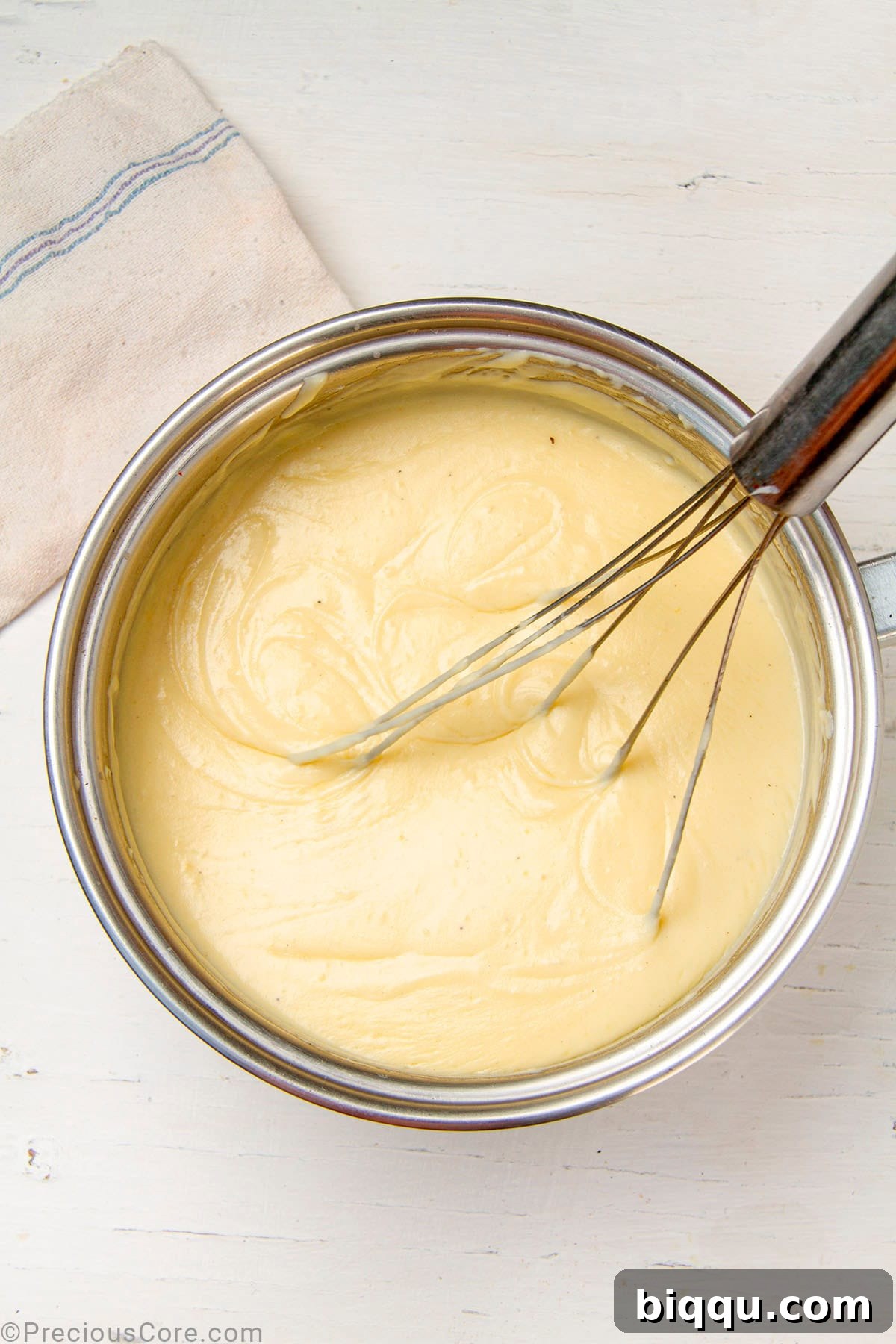 A rich, smooth, and creamy homemade béchamel sauce coating a spoon in a pot, indicating perfect consistency.