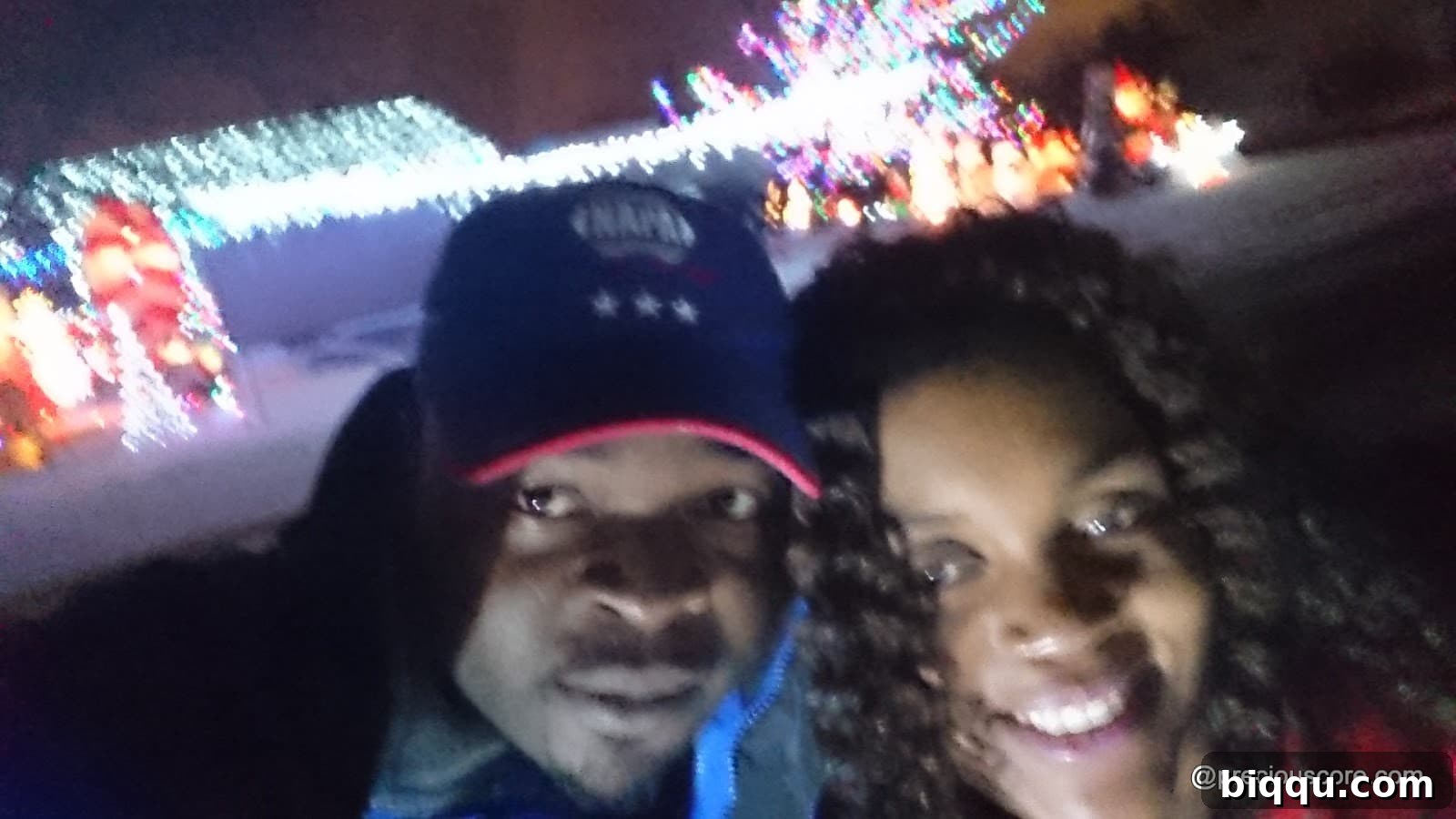 Family members posing happily beside a brightly lit Christmas decoration