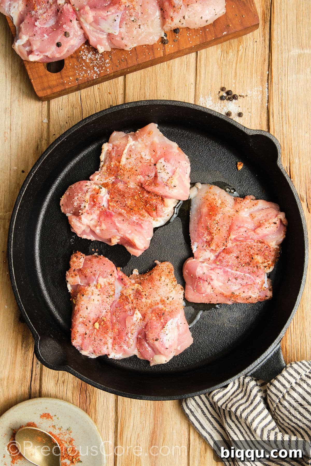 Chicken thighs sizzling in a hot cast iron skillet.