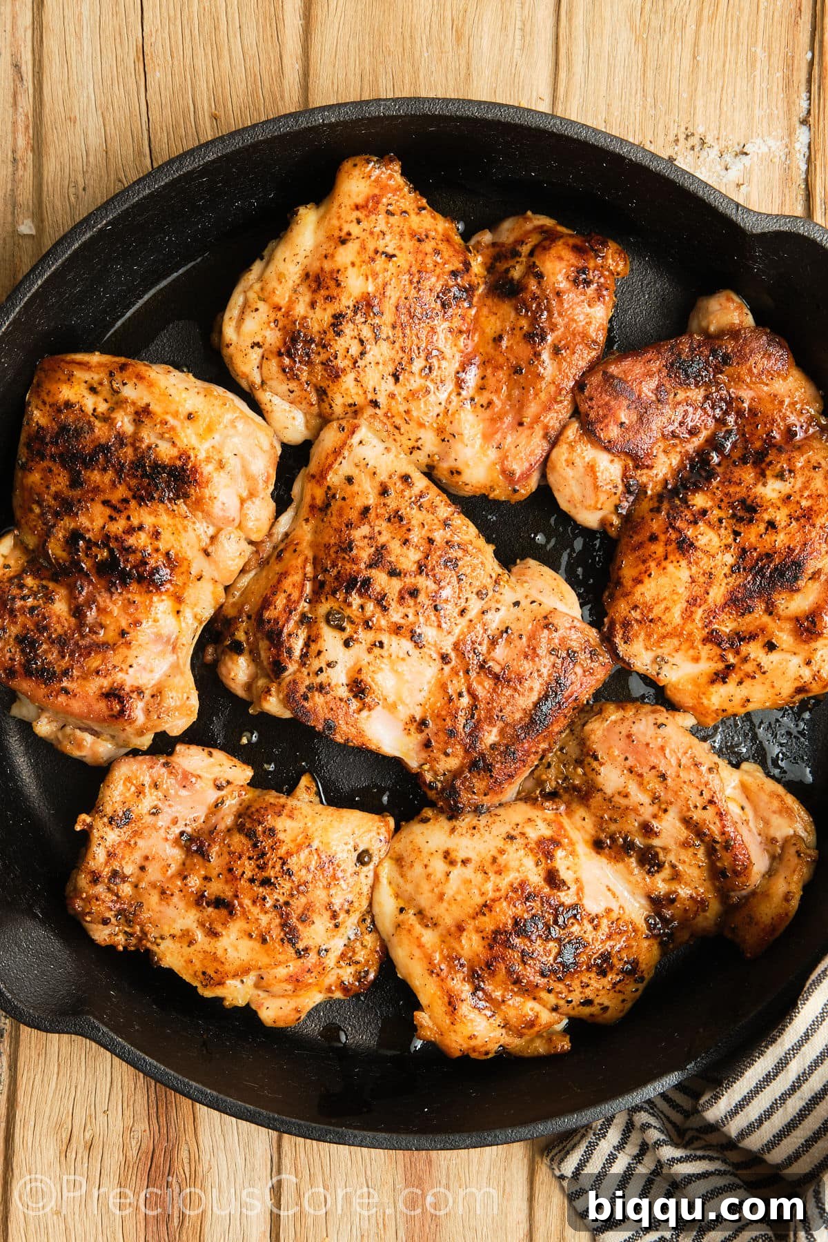 Expertly seared boneless chicken thighs flipped in a skillet, showing off their golden crust.