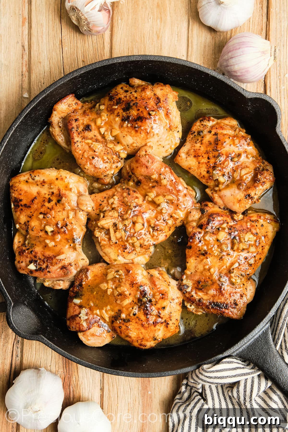 Final stage of cooking, with chicken thighs bathed in garlic butter in a cast iron skillet.