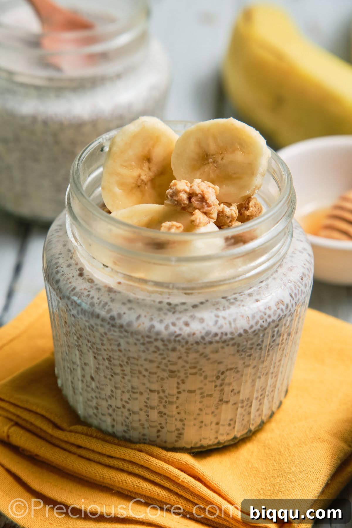 Close-up of a jar of creamy banana chia pudding, topped with fresh banana slices and walnuts.