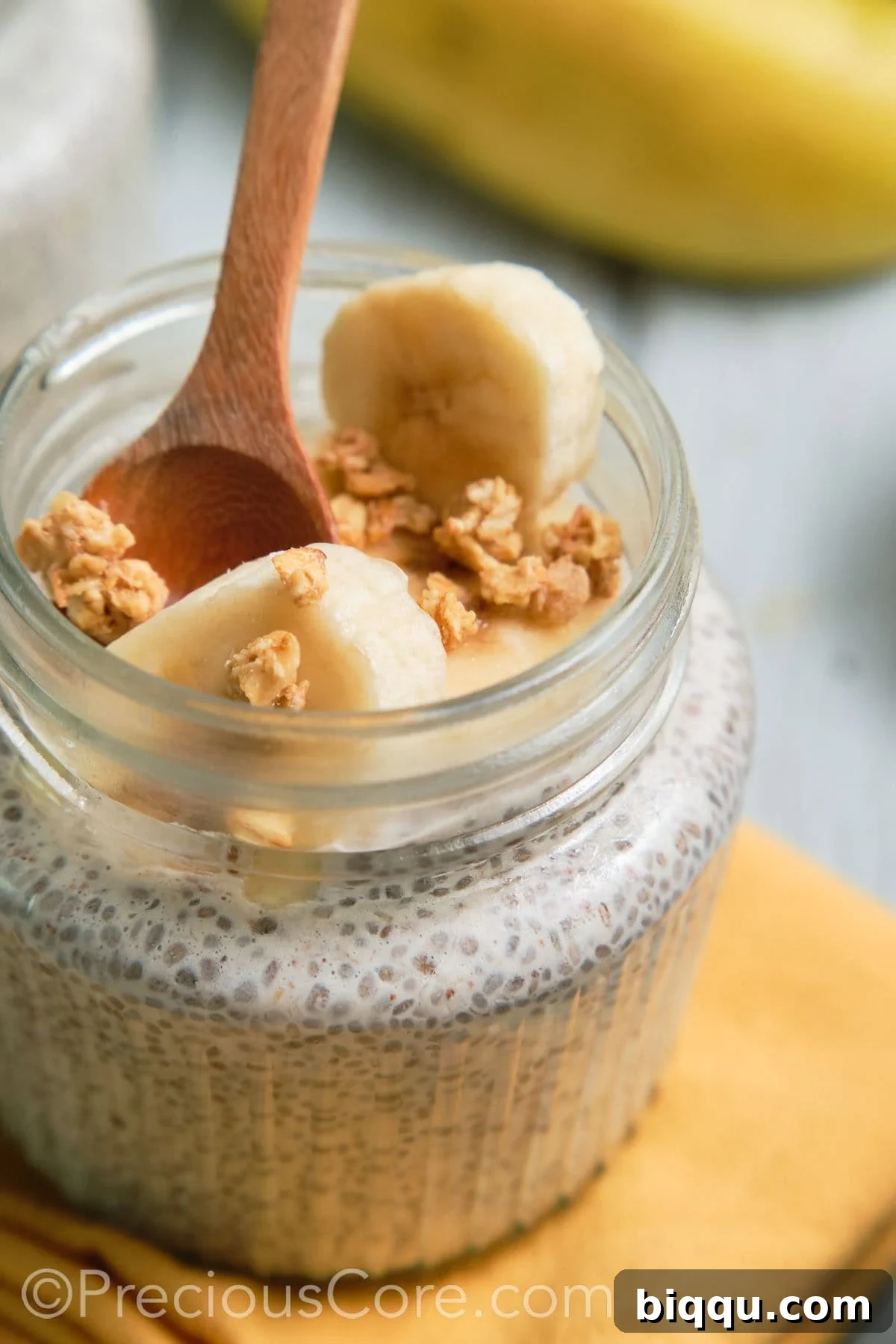 A spoon dipping into a jar of creamy banana chia pudding, ready to be eaten.