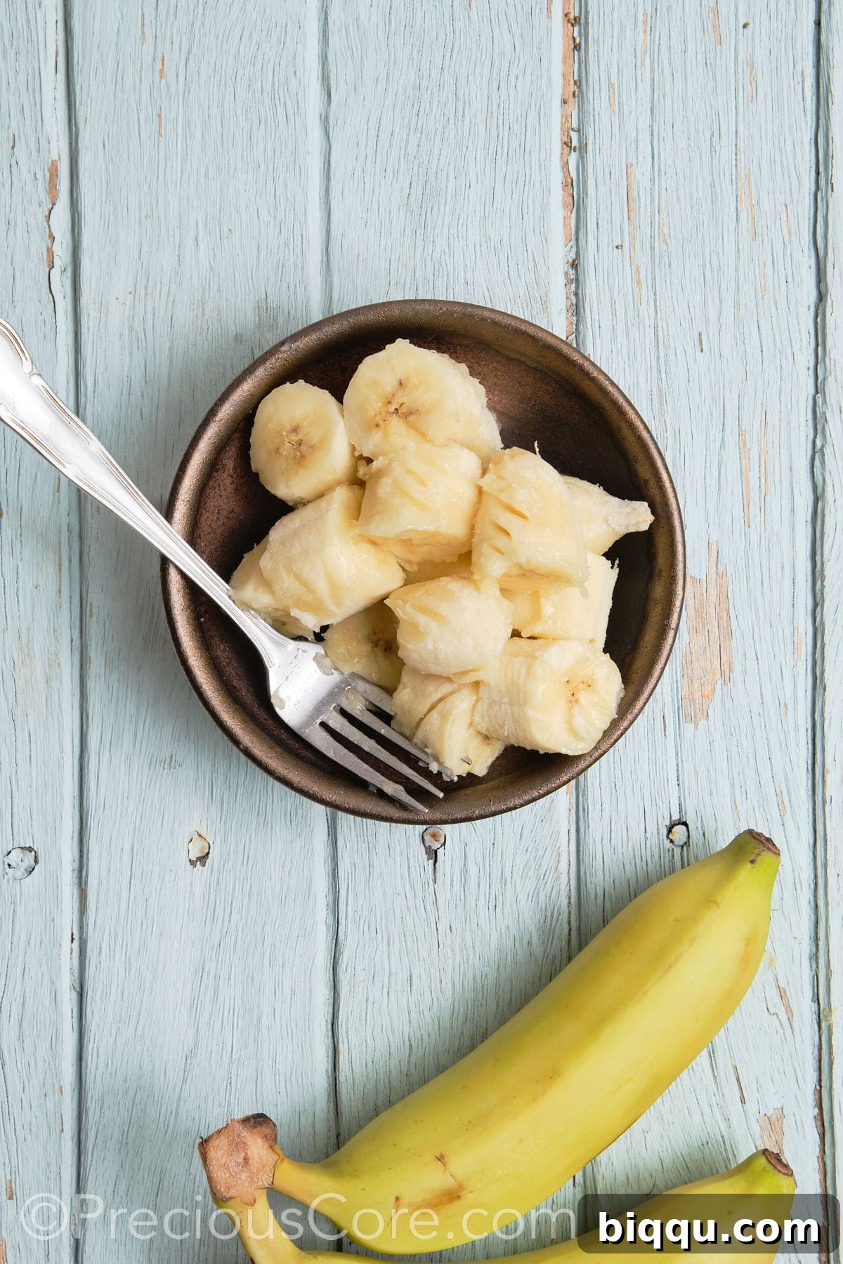 Mashing ripe bananas in a bowl with a fork.