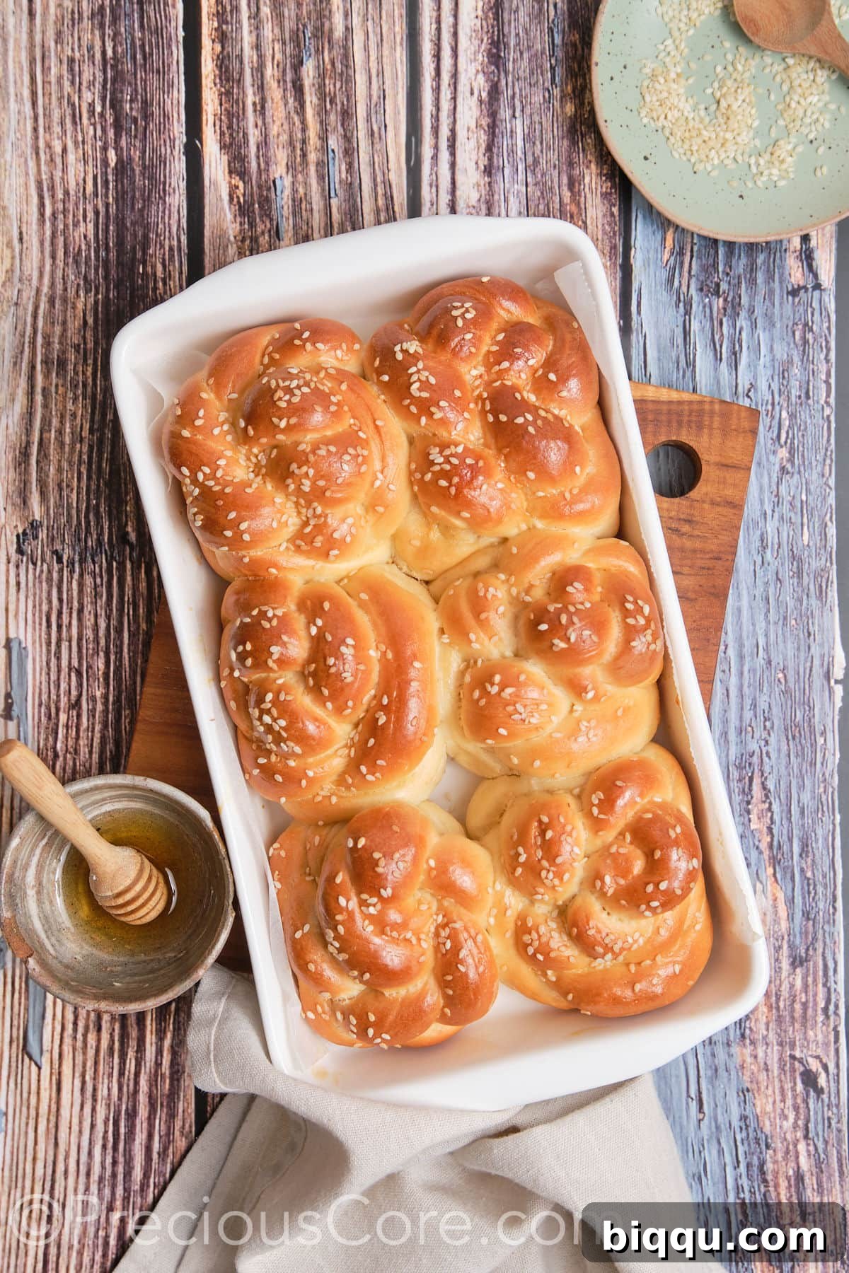 A tray of freshly baked, golden brown challah rolls.