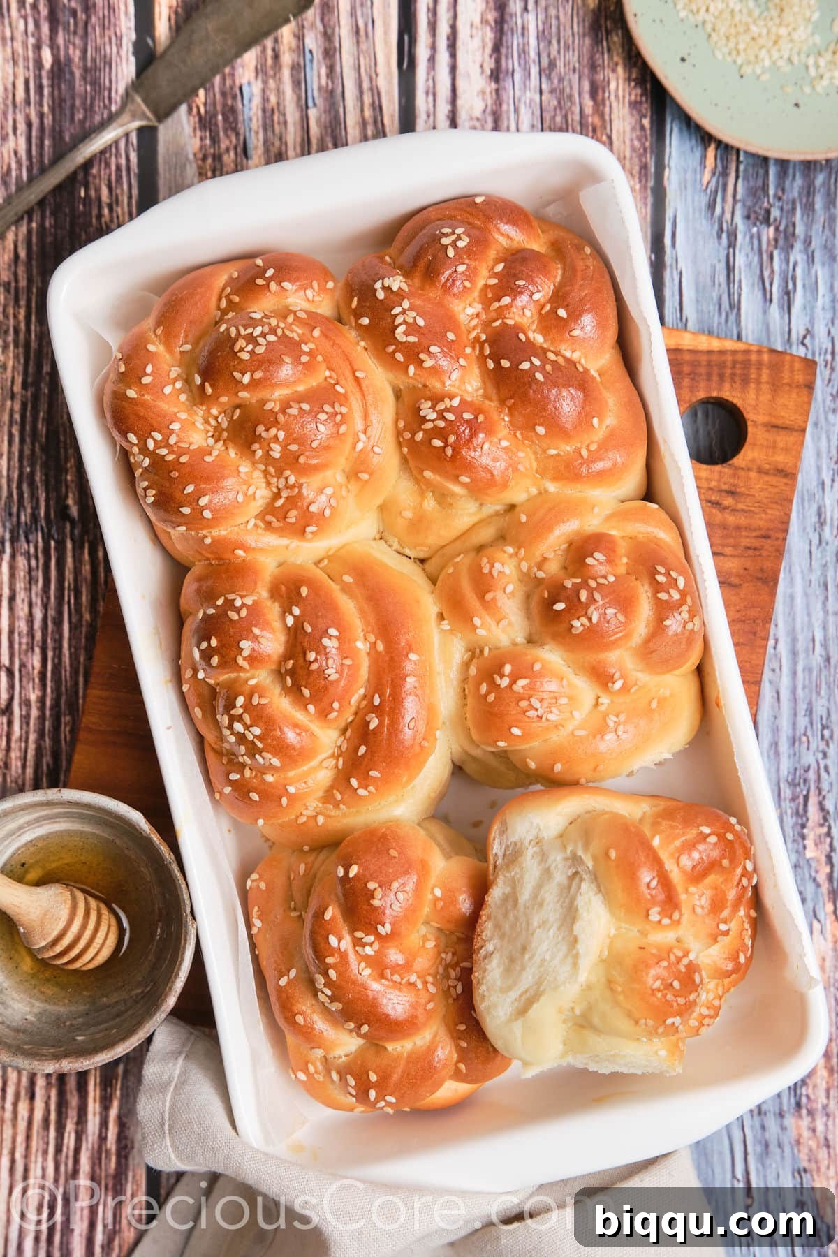 One challah roll being pulled apart to showcase its soft, fluffy internal texture.