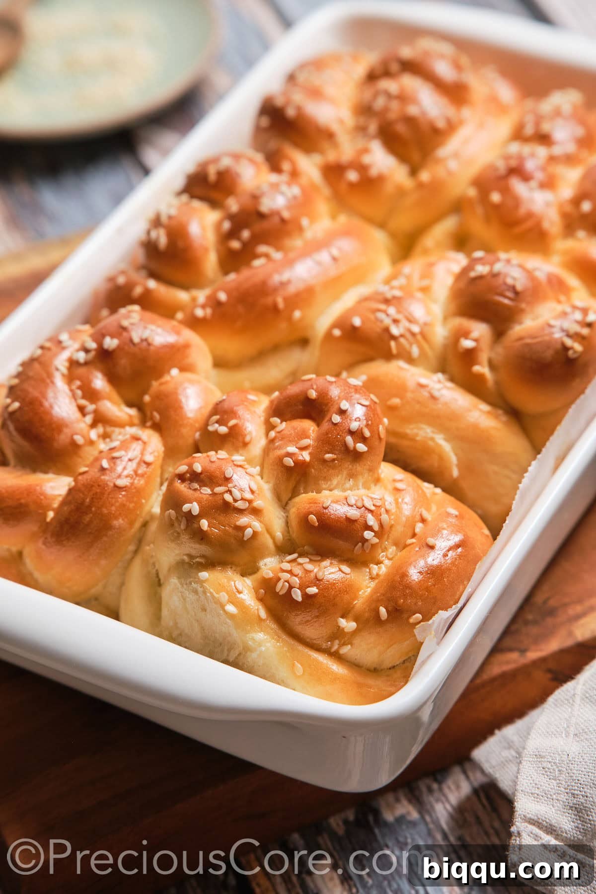 A baking dish filled with a generous batch of perfectly baked homemade challah rolls.