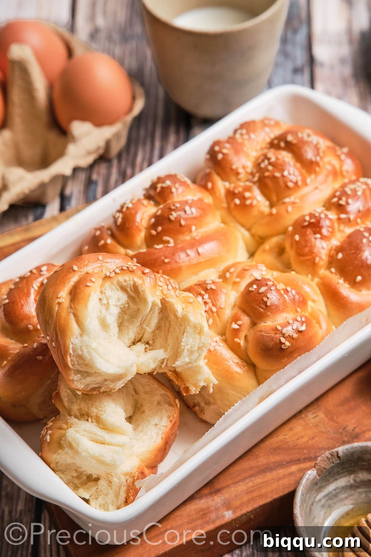 A challah roll cut in half, revealing its soft, airy, and pillowy texture.