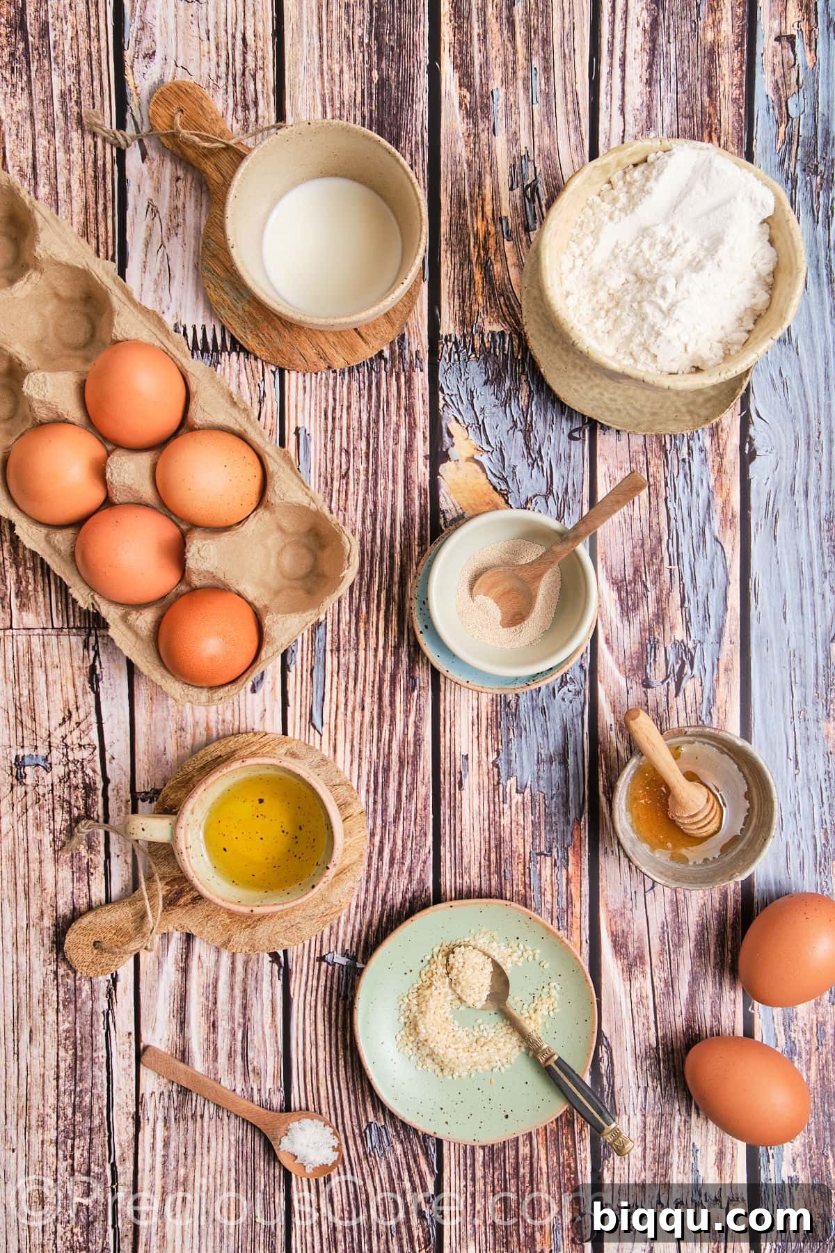 A display of fresh ingredients for Challah Dinner Rolls, including flour, eggs, oil, honey, yeast, and milk.