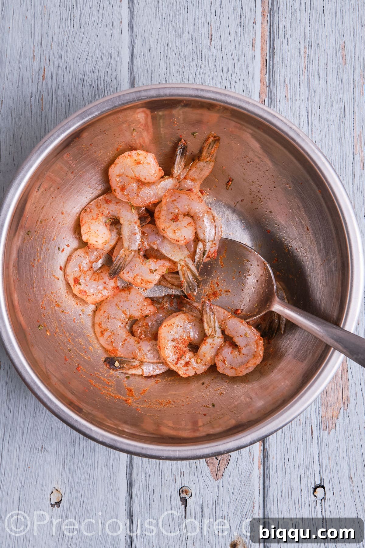 Succulent shrimp, thoroughly coated and tossed with vibrant Cajun seasoning, glistening on a plate.