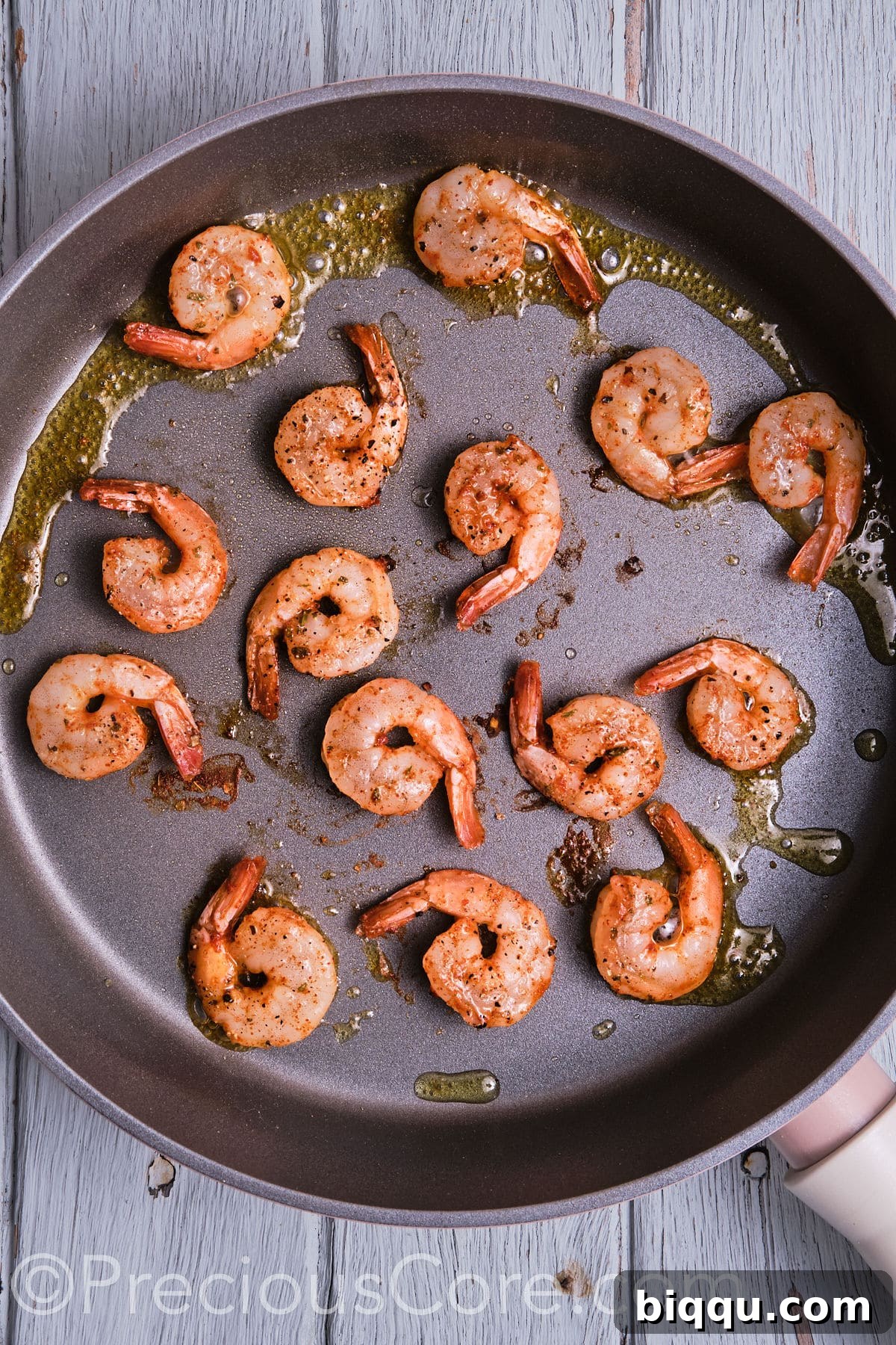 Cajun-seasoned shrimp sizzling and cooking to perfection in a hot cast-iron pan.