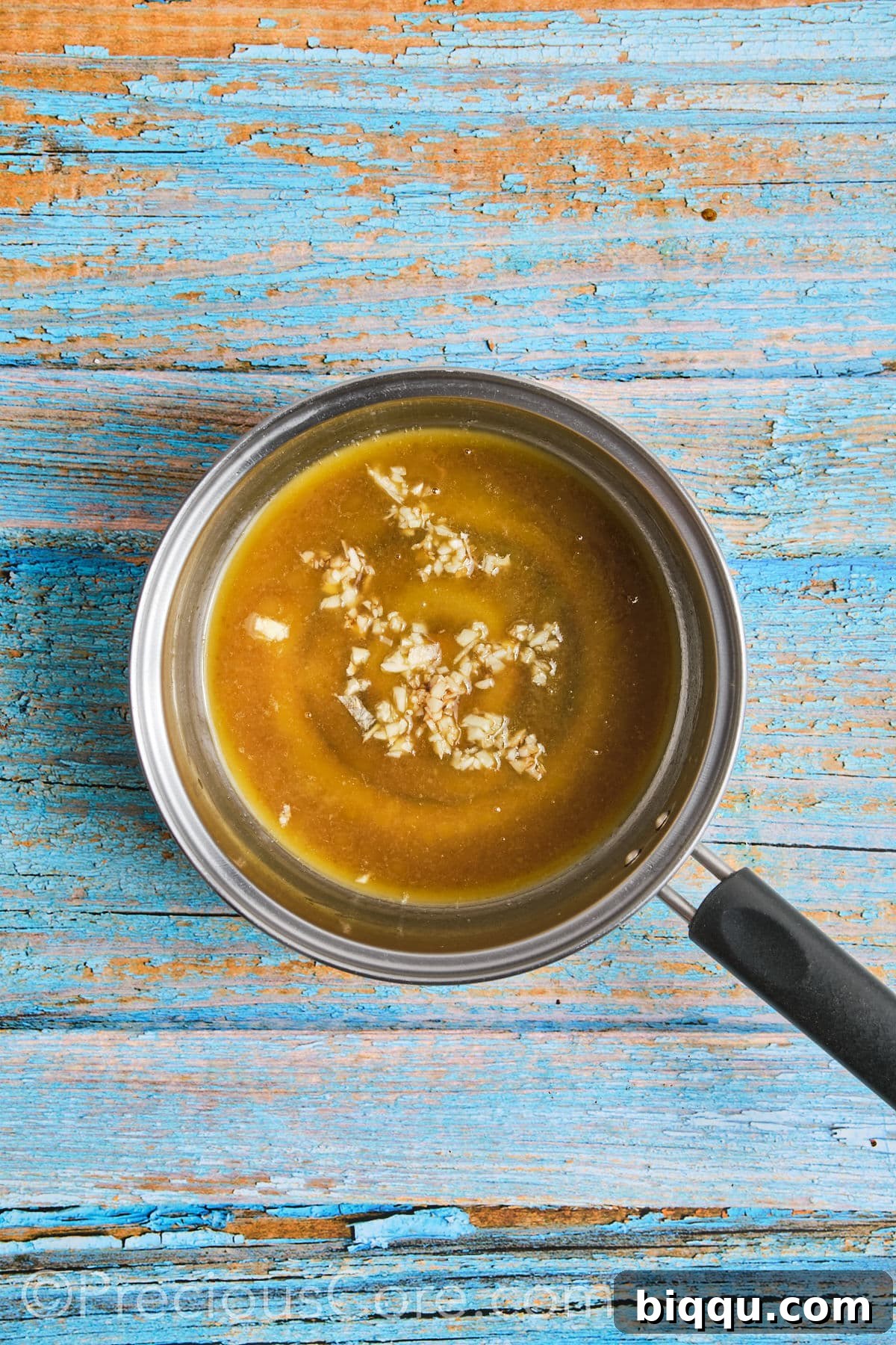 The honey butter sauce ingredients gently simmering in a small saucepan over medium heat.