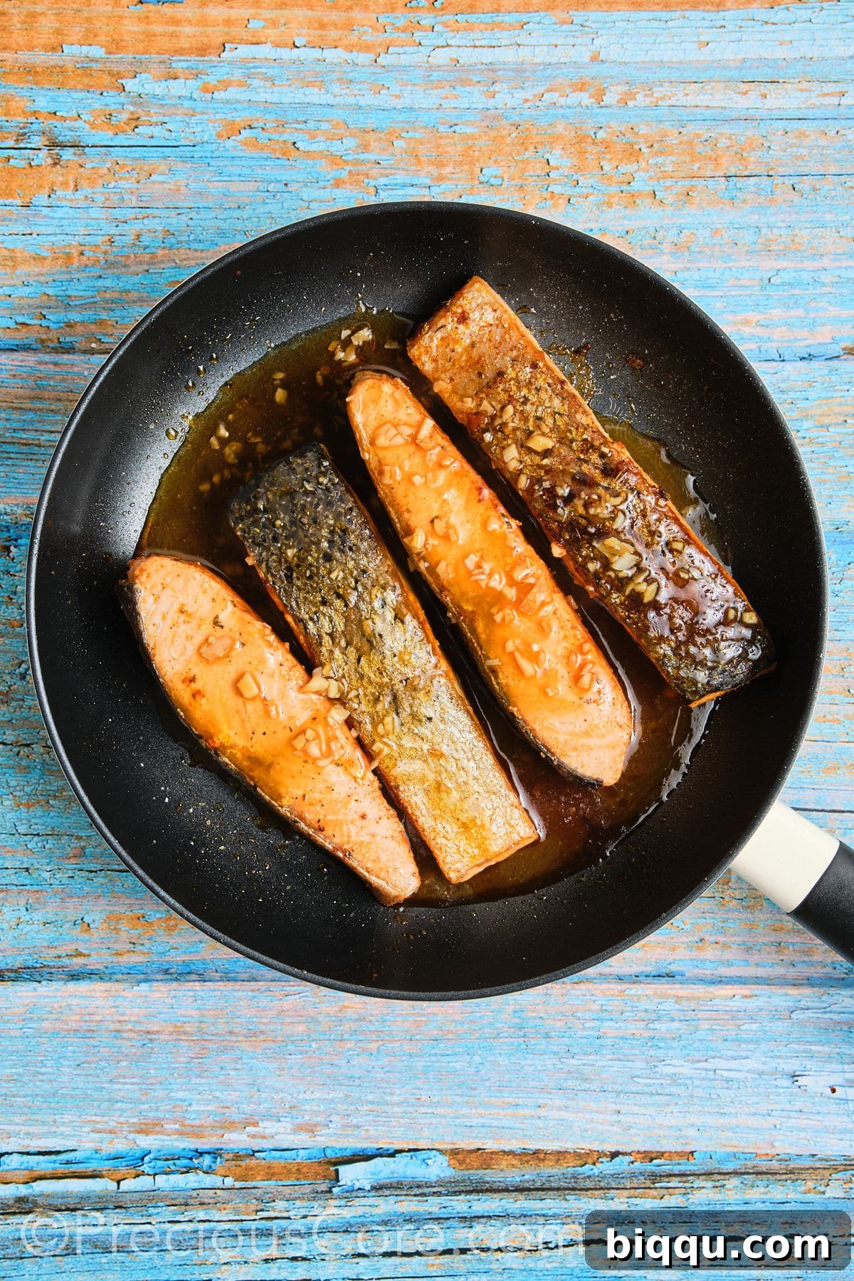 Salmon fillets gently simmering in the delectable honey butter sauce in a skillet, absorbing all the flavors.