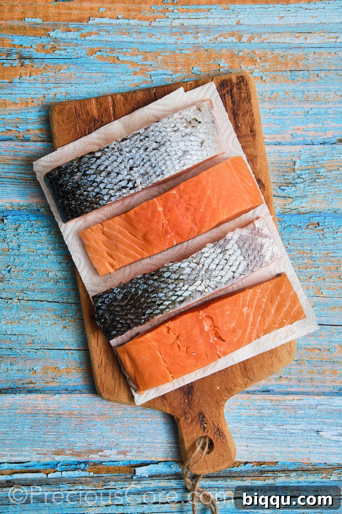 A hand gently patting a salmon fillet dry with a paper towel, emphasizing the crucial first step.