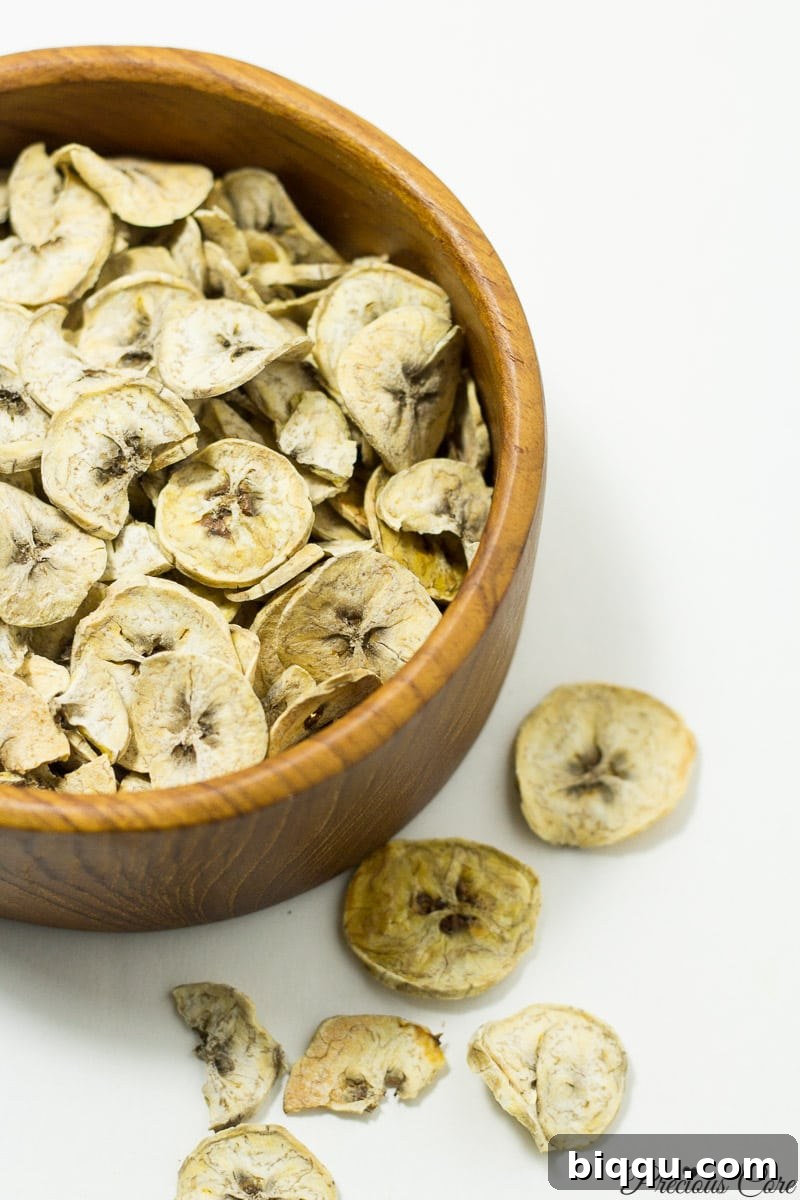 Wooden bowl of dried plantains, ready for grinding into flour.