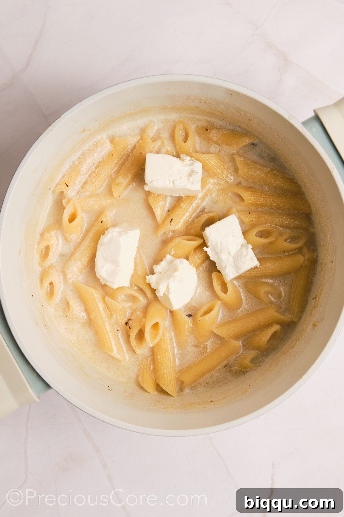 Cubed cream cheese melting into the creamy pasta, ready to be stirred in for extra richness.