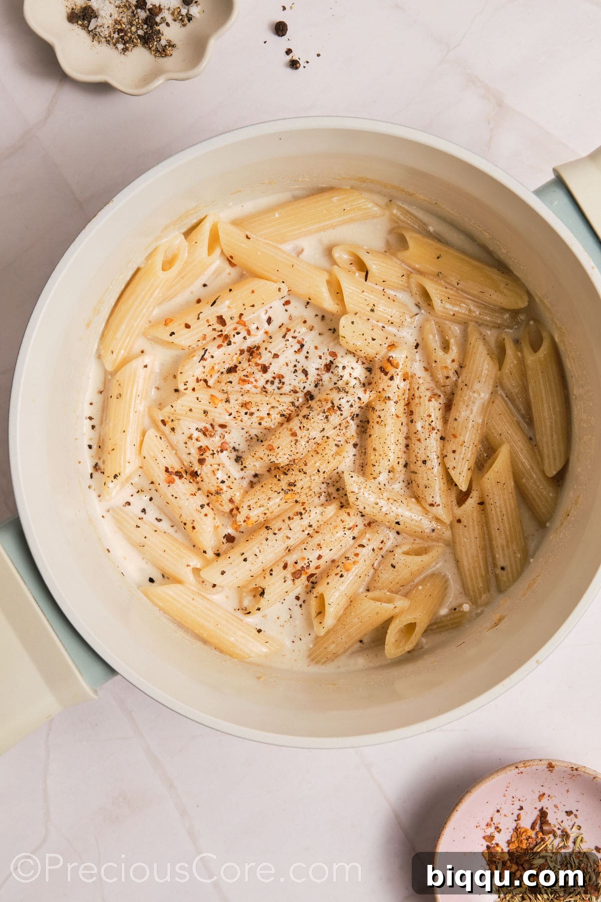 A sprinkle of seasoning being added to the one-pot creamy pasta to enhance its flavor profile.