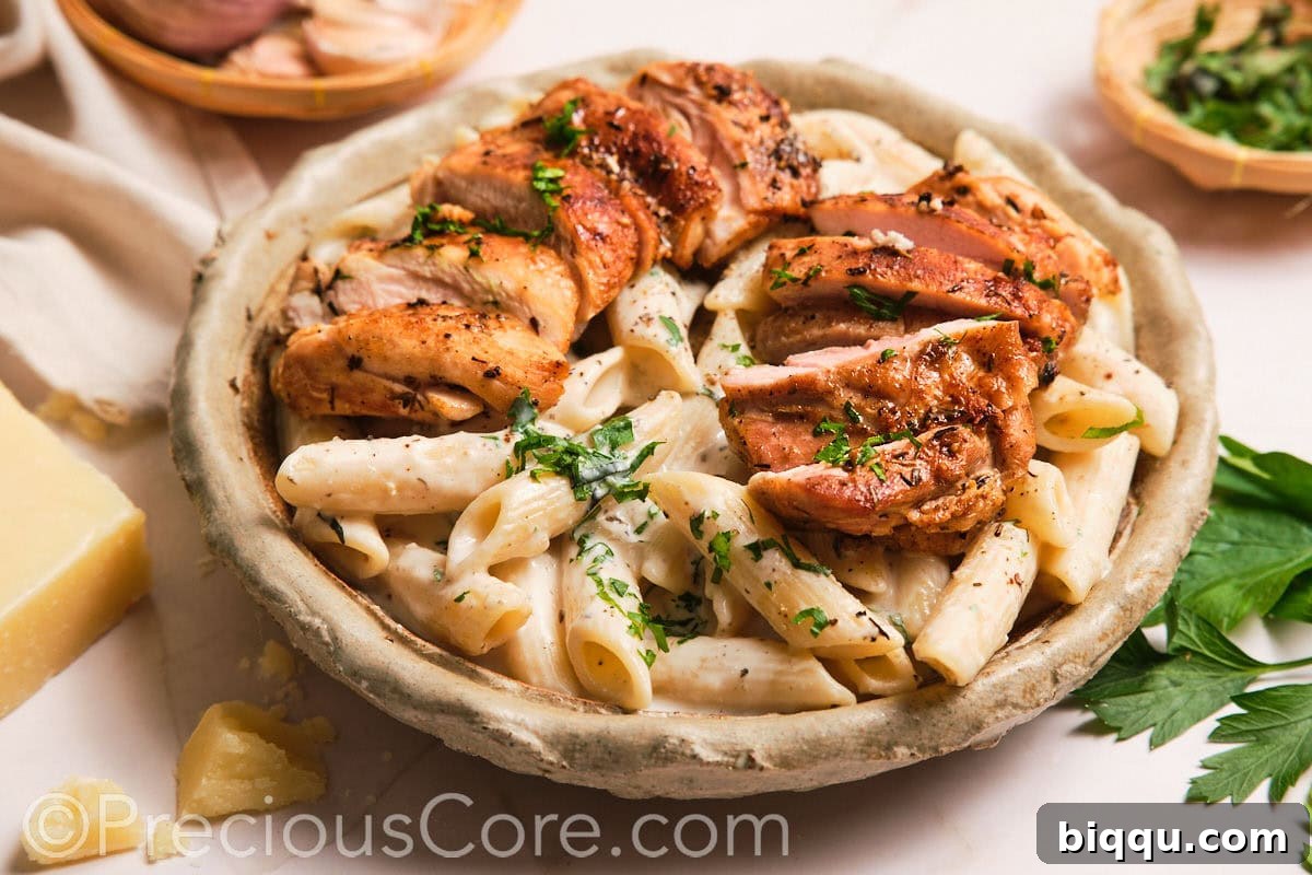 Creamy pasta elegantly topped with perfectly sliced boneless chicken thighs, ready for serving.