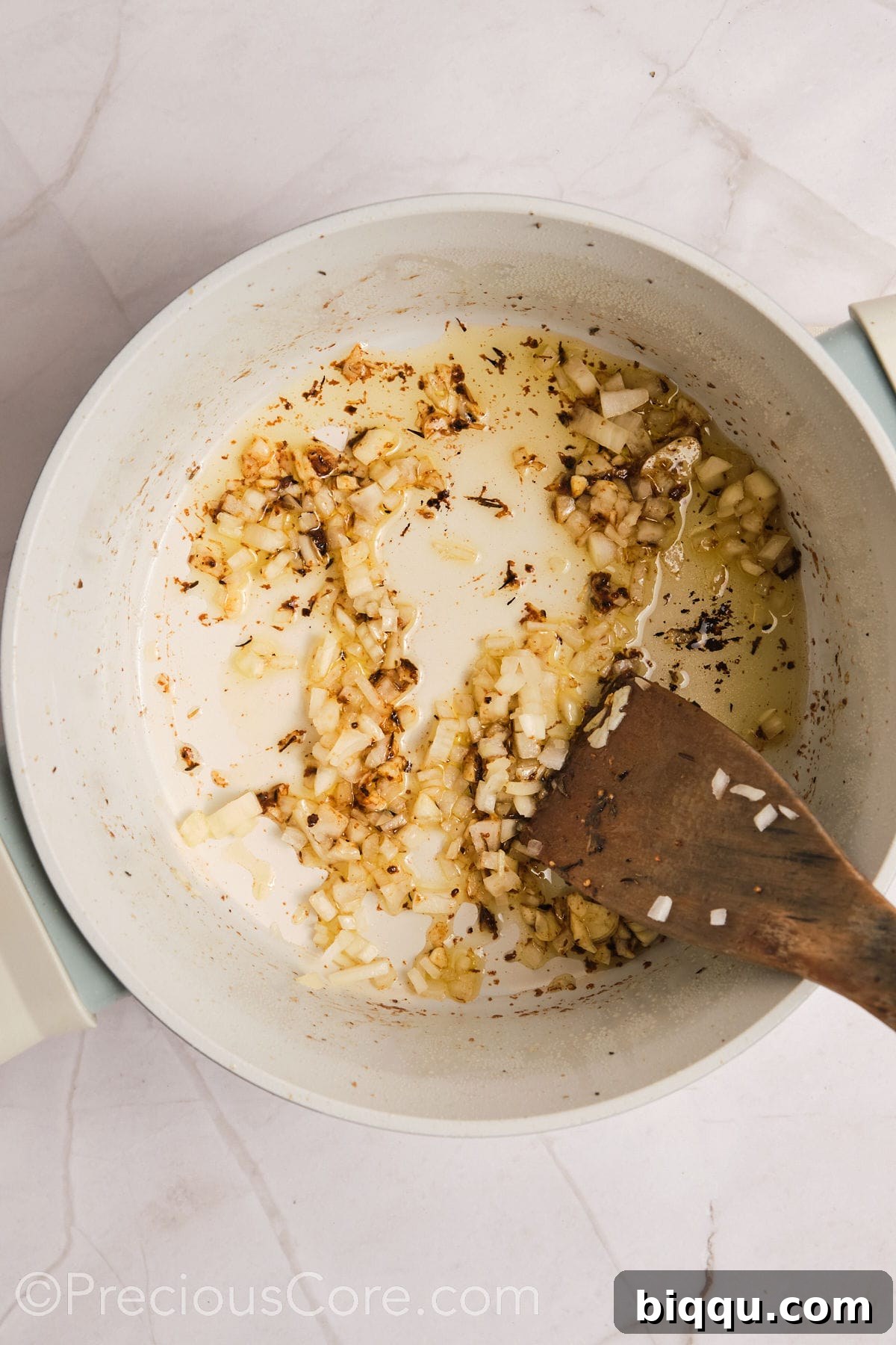 Diced onions and minced garlic gently sautéing in a pot, becoming translucent and fragrant.