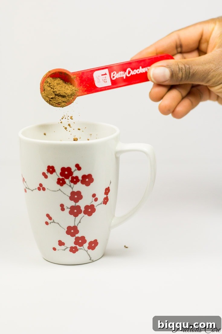 Cocoa powder pouring into a floral mug, a key ingredient for rich hot chocolate.
