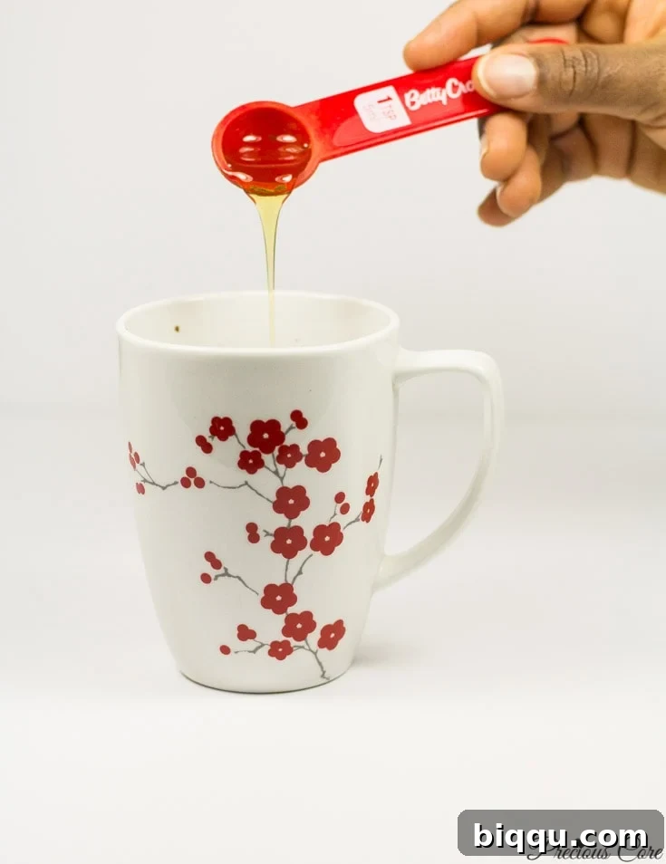 Honey pouring into a floral mug, adding natural sweetness to the hot chocolate.