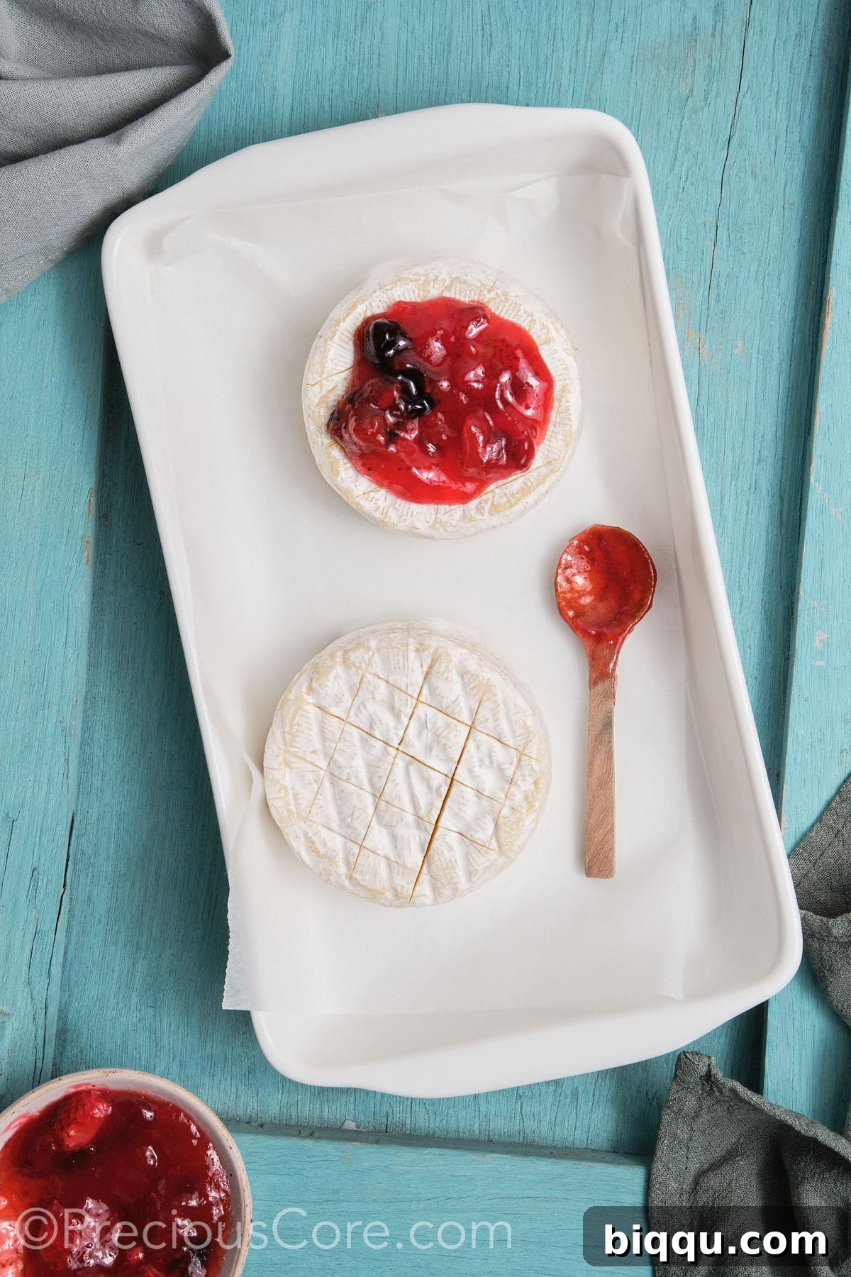 Brie transferred to a baking dish and topped with preserves.,