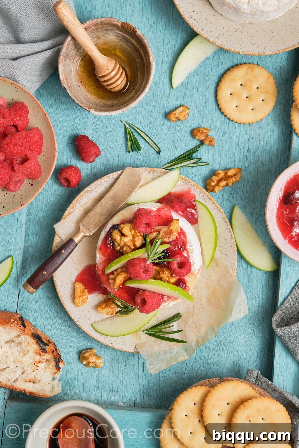 Baked brie and preserves topped with raspberries, fresh raspberries, and apple slices.