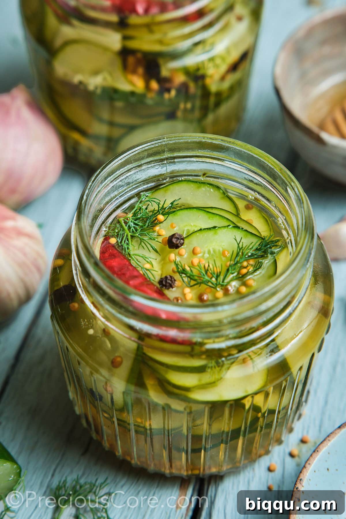 Quick pickled cucumbers in a mason jar with peppercorns on top.