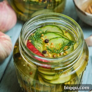 Quick pickled cucumbers in a mason jar with peppercorns on top.