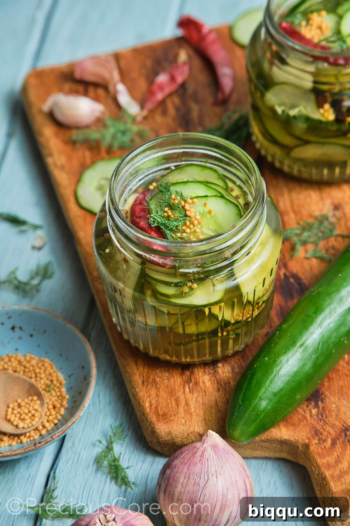 Wide shot showing cucumbers in a jar and other ingredients all around it.