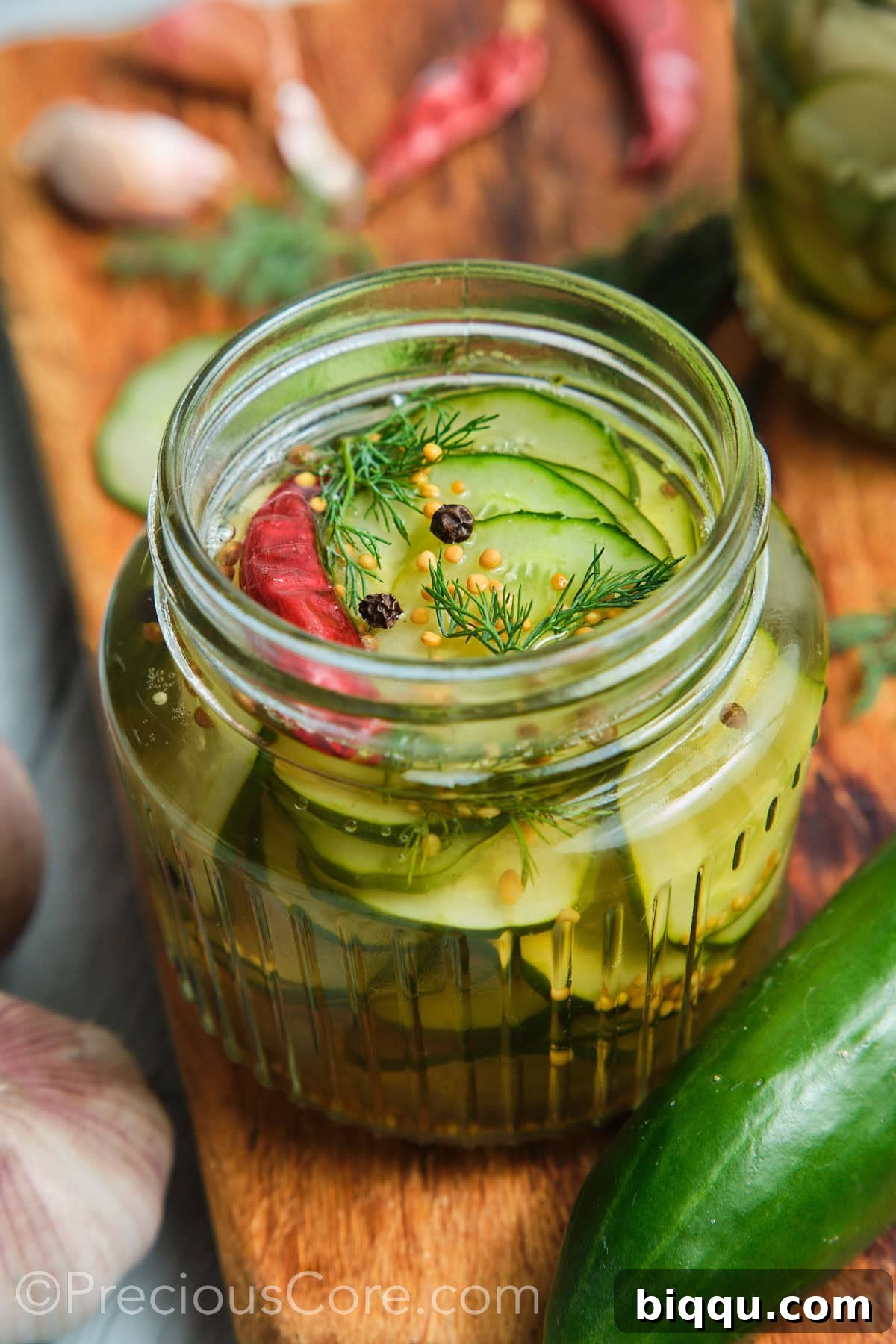Close-up shot of cucumber in a brine topped with peppercorns and dill.