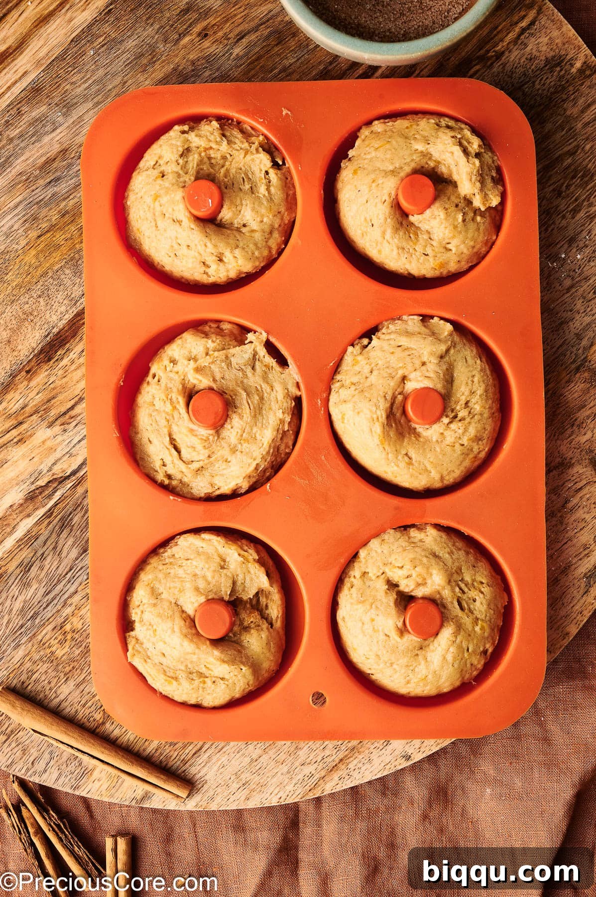 Pumpkin spice batter piped into doughnut pan.