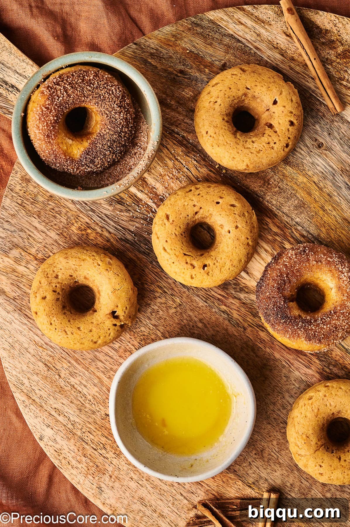 Two pumpkin doughnuts coated in cinnamon sugar.