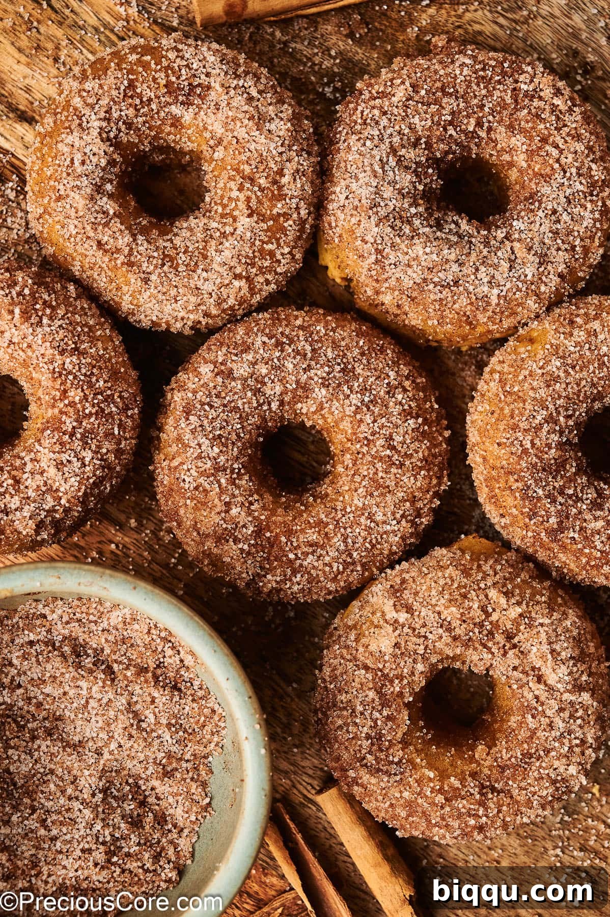 Cinnamon sugar pumpkin doughnuts on a wooden board.