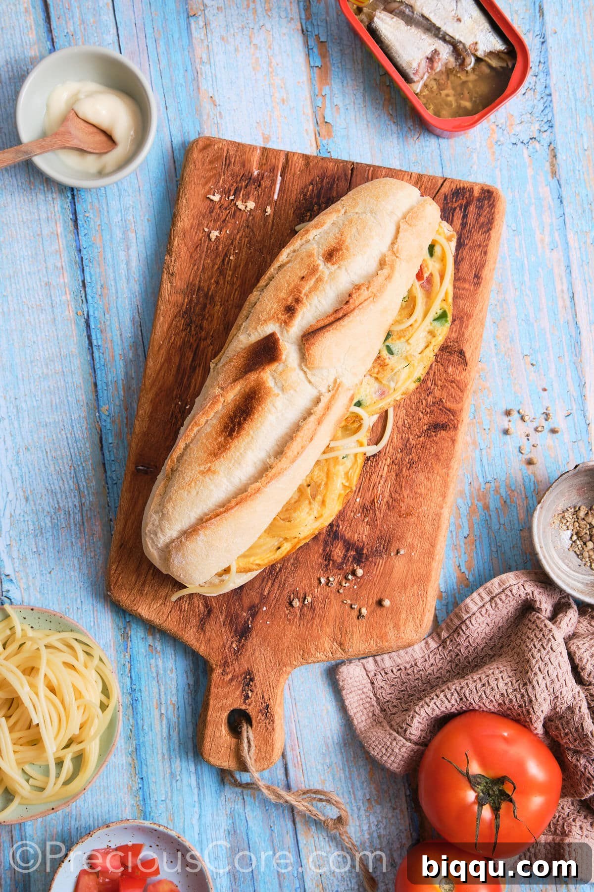A close-up shot of a fully assembled Cameroonian Spaghetti Omelette Sandwich, tightly wrapped and ready to be enjoyed, showing its golden-brown bread and inviting texture.